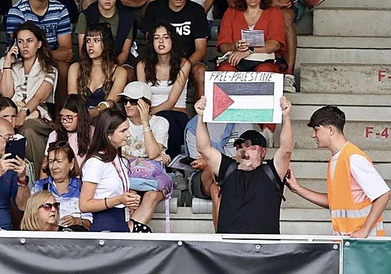 Un hombre muestra la bandera de Palestina durante la participación de un jinete israelí en el Hípico de Gijón.
