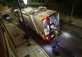Un operario vuelca un cubo de la basura en el camión de recogida en la calle de Leopoldo Alas.