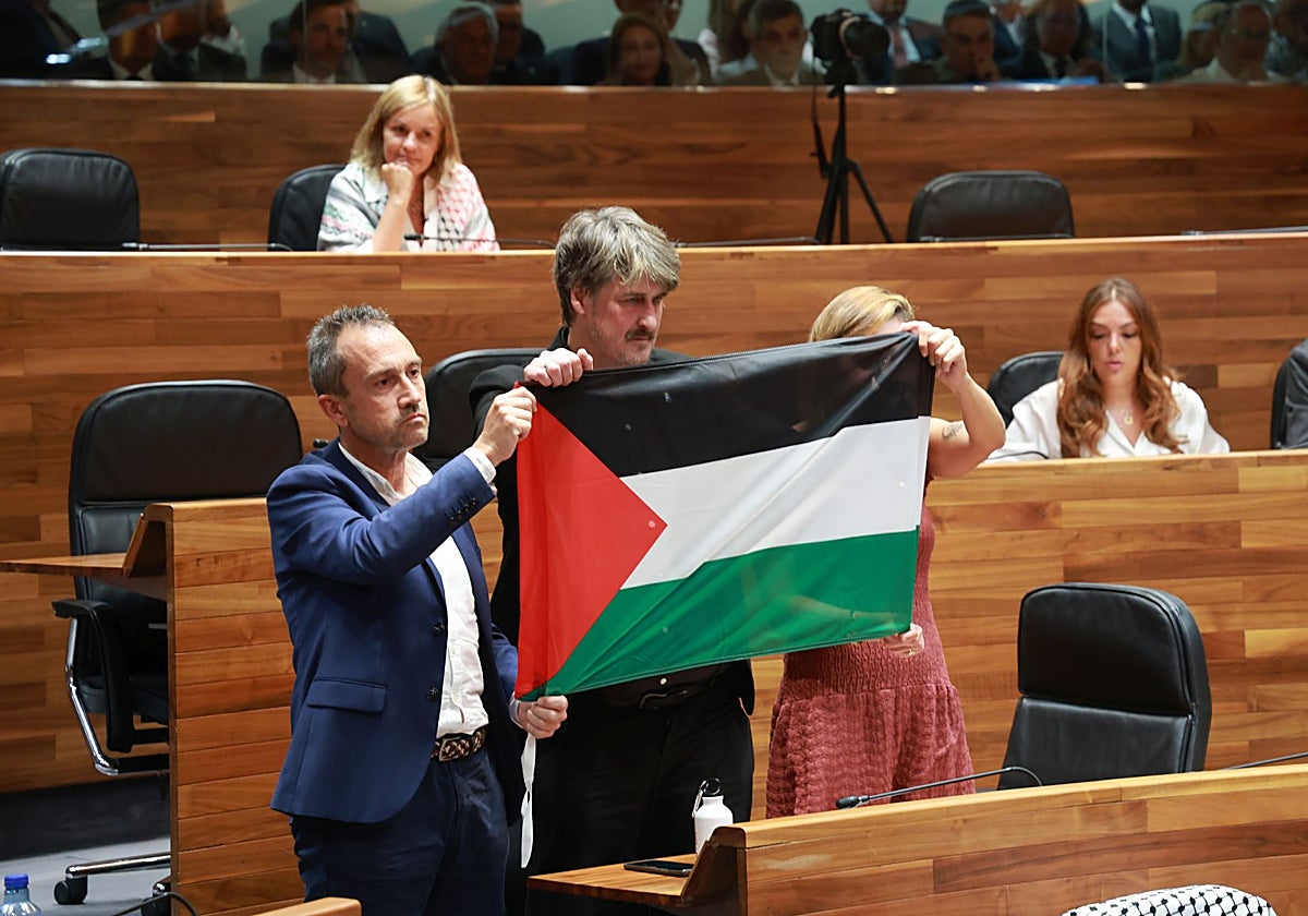 El consejero de Ordenación del Territorio, Ovidio Zapico, y los diputados de IU-Convocatoria por Asturies, Xabel Vegas y Delia Campomanes, sostienen la bandera de Palestina al inicio del pleno institucional del Día de Asturias.