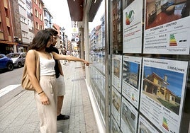 Dos jóvenes consultan las ofertas de una inmobiliaria de Gijón.