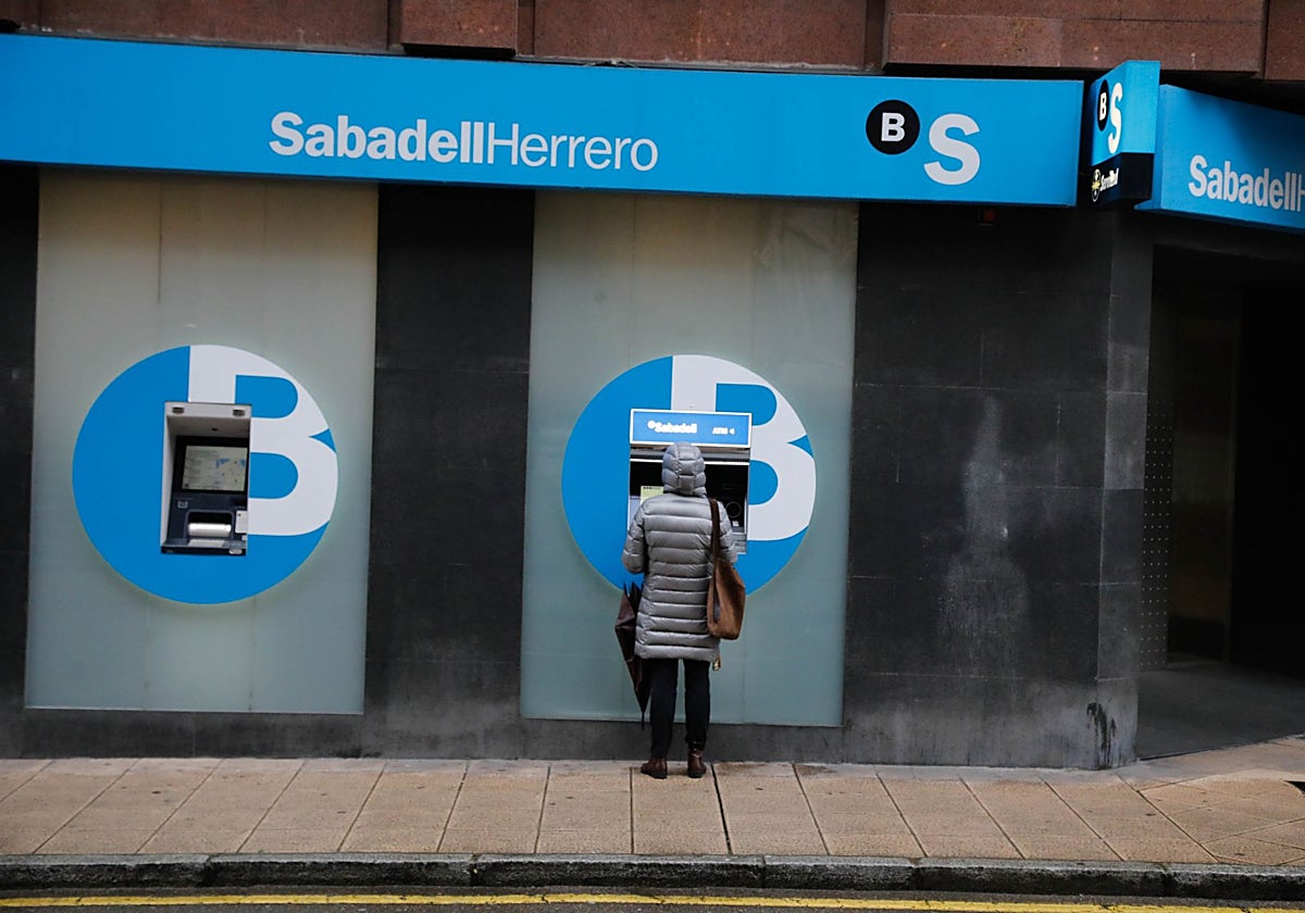 Una mujer opera en un cajero del Sabadell Herrero, en Gijón.
