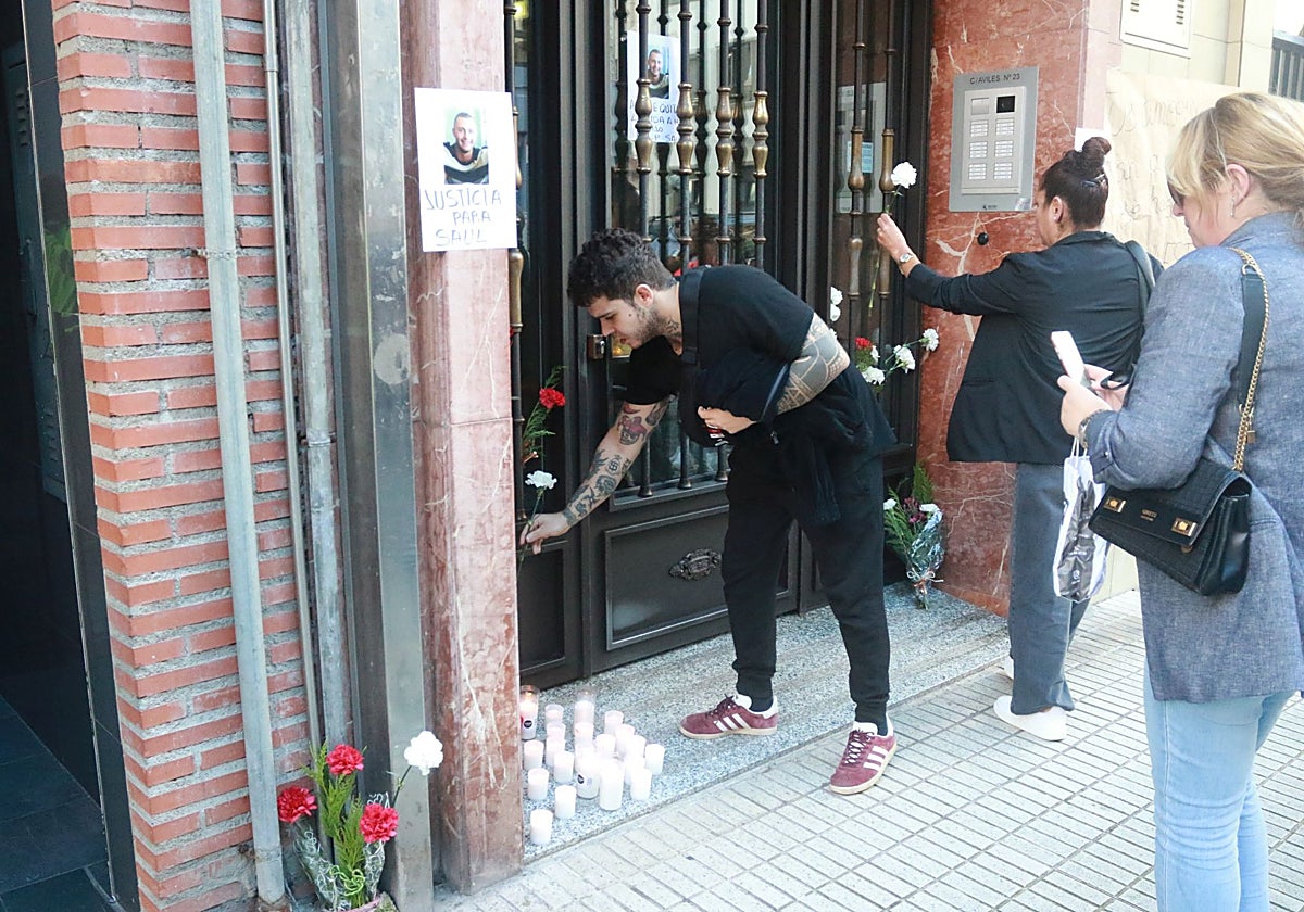 Amigos de Saúl Iglesias colocan flores y velas en el portal de la calle Avilés en el que falleció en octubre de 2023.
