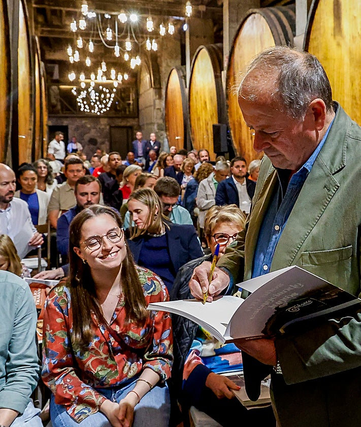 Imagen secundaria 2 - Samuel Trabanco firma el libro 'Trabanco, 100 años escanciando juntos' en el llagar El Túnel, en una cita familiar en la que conversó con el autor Pachi Poncela, en la foto superior.