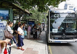 Un autobús, con el carte del servicio mínimo, a punto de recoger a varios usuarios en el centro de Oviedo.