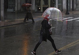 Una mujer camina bajo la lluvia de este lunes en Gijón.