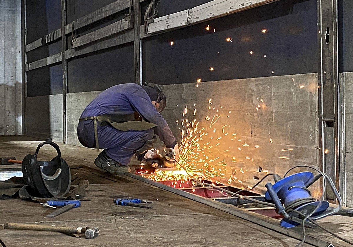 Un soldador repara la plataforma de un camión del transporte en un taller de Gijón.
