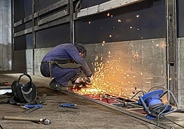 Un soldador repara la plataforma de un camión del transporte en un taller de Gijón.