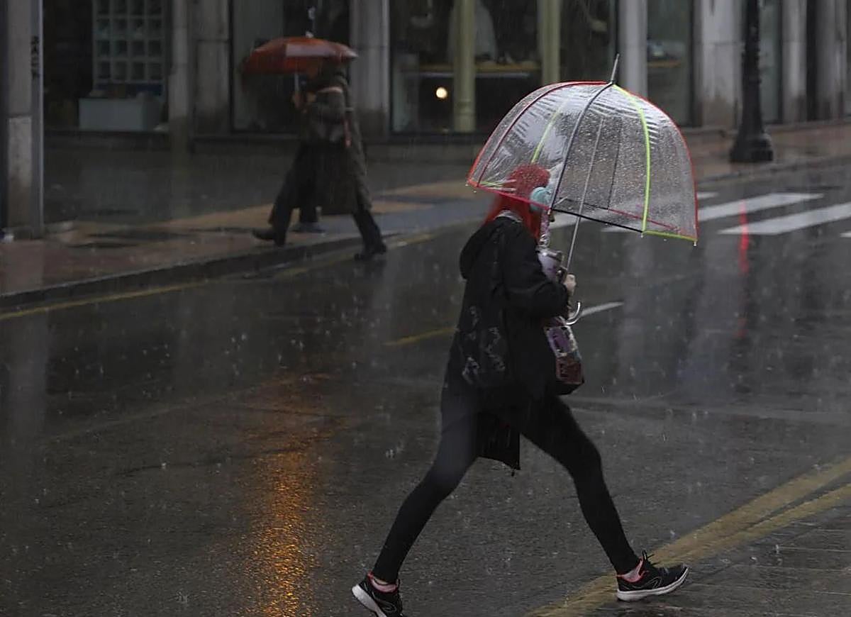 Una mujer camina bajo la lluvia de este lunes en Gijón.