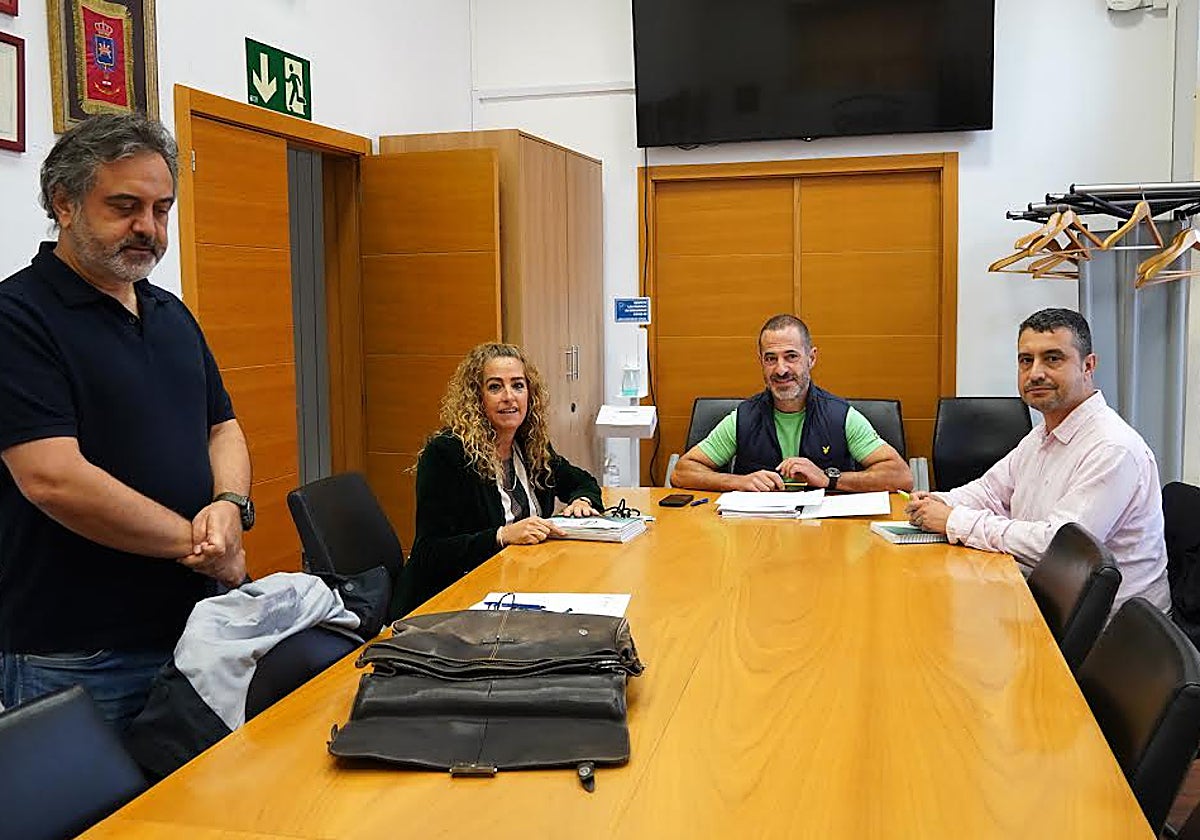 El portavoz popular, de pie, ante su negativa a fotografiarse sentado en la mesa con el alcalde, en el centro.
