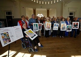 Protagonistas de la muestra 'Sois muy grandes,' junto a organizadores y voluntarios de Cruz Roja, portan los cuadros con sus retratos tras la jornada en la Escuela de Comercio.