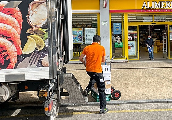 Un empleado descarga un camión a las puertas de un supermercado asturiano.