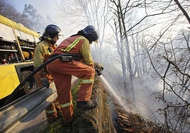 Bomeros realizando trabajos de extinción de un incendio forestal en Mieres.