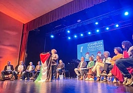 La coordinadora de IU de Mieres se dirige a los vecinos con el equipo de gobierno en el escenario de la casa de la Cultura