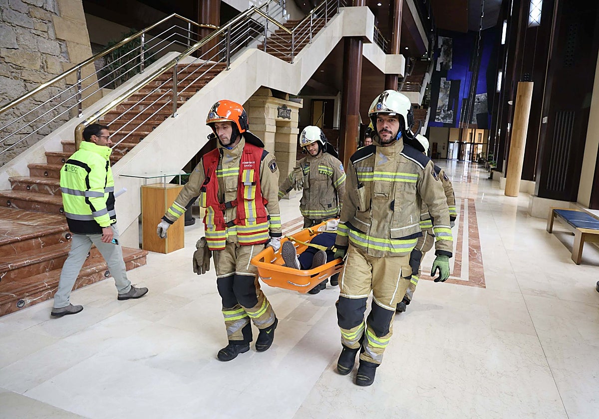 Los bomberos sacan a una mujer en camilla que, supuestamente, se había desvanecido.