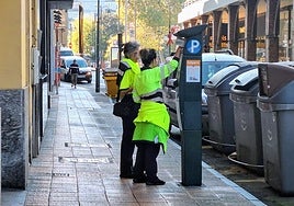 Dos trabajadoras de la empresa encargada del servicio de la ORA en Avilés junto a un parquímetro.