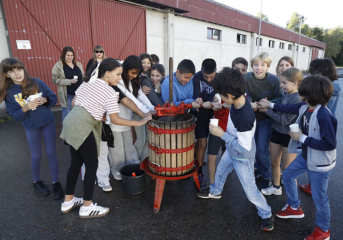 Los niños prensando la magaya en la jornada educativa dentro del Día Internacional de la Manzana.