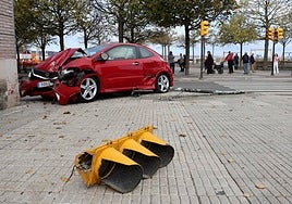 Coche accidentado contra el Museo del Ferrocarril y, en primer plano, trozo del semáforo que se llevó por delante en la avenida de José Manuel Palacio, en Gijón.