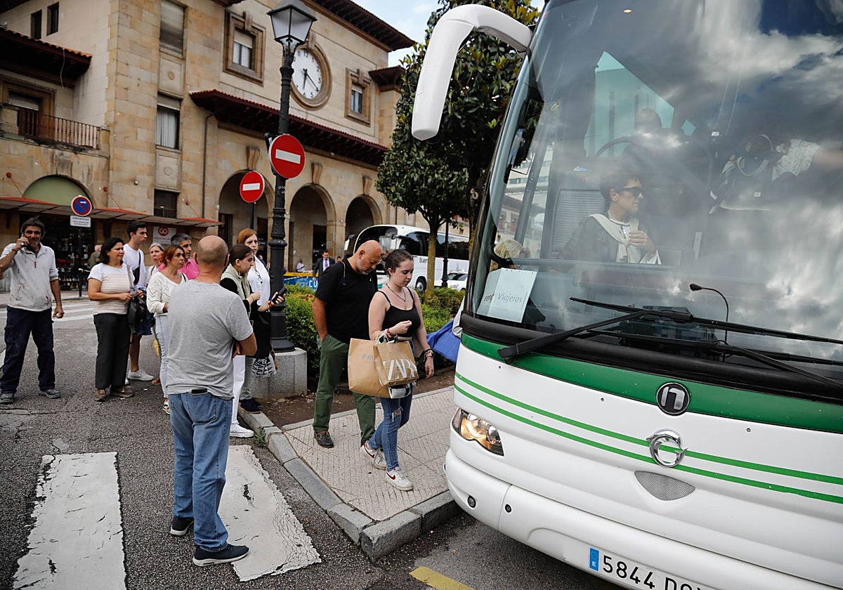 Viajeros subiéndose a un autobús enfrente de la estación de tren del Norte, en Oviedo.