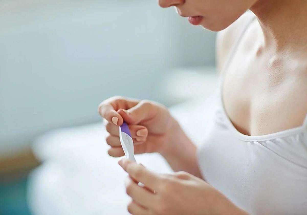 Una joven sostiene un test de embarazo.