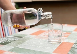 Una persona sirve un vaso de agua.
