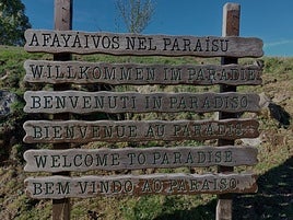 Cartel con «Bienvenidos al Paraíso» en varios idiomas en la vega de Brañagallones.
