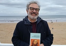 El escritor Ovidio Parades con su libro entre las manos en el Muro de Gijón.