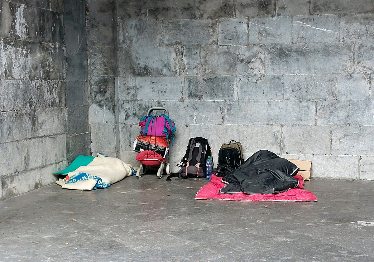 Una persona sin hogar duerme en la calle junto a sus pertenencias.