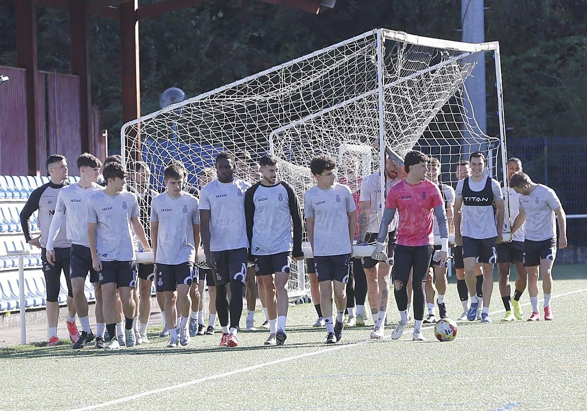 Los jugadores del Real Avilés mueven una portería durante un entrenamiento de esta semana en La Toba 2.