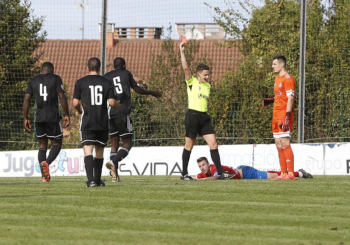 El árbitro enseña la roja a Traoré con Madeira en el suelo.