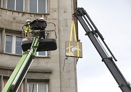 Una grúa retira el logotipo del asturcón de la fachada del edificio.