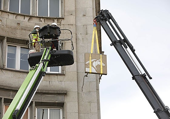 Una grúa retira el logotipo del asturcón de la fachada del edificio.