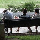 Varios jóvenes sentados en el banco de un parque.