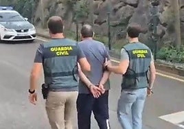 El detenido, custodiado por dos guardia civiles en el acuartelamiento de Gijón.