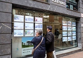 Dos personas observan en escaparate de una inmobiliaria, en Oviedo.