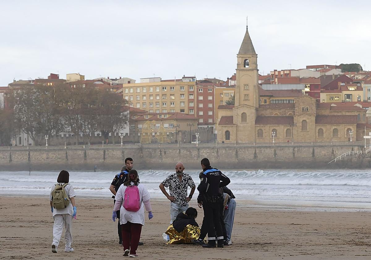 Agentes de la Policía Local y sanitarios atienden a la joven indispuesta en la playa de San Lorenzo.