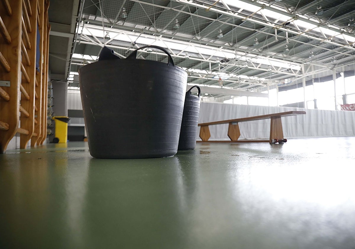 Cubos para recoger el agua de las goteras en un pabellón deportivo de Gijón.