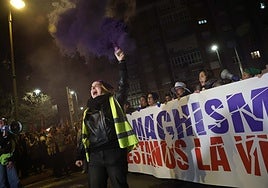 Una de las integrantes de la Plataforma Asturias Feminista, con una bengala malva, ante la pancarta de cabecera.