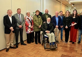 José Luis Pérez, en silla de ruedas en el centro, rodeado de su mujer Mina, la alcaldesa, José Ramón Fiaño (Caja Rural de Gijón), Miguel Llanos (presidente de Les Caseríes) y representantes de todos los grupos políticos municipales salvo Vox.