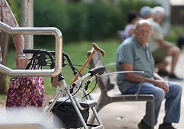 Personas mayores, una de ellas con andador, en un parque. 