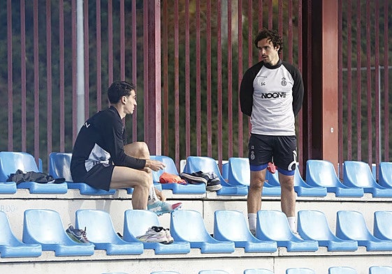 Pelayo Suárez, a la derecha, en la grada de La Toba junto a Adri Gómez en el entrenamiento de este miércoles del Real Avilés.