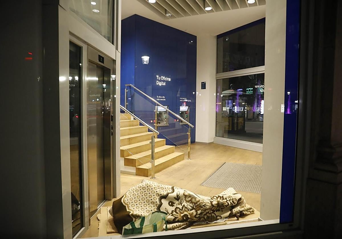 Una persona sin hogar duerme en un cajero de Gijón.