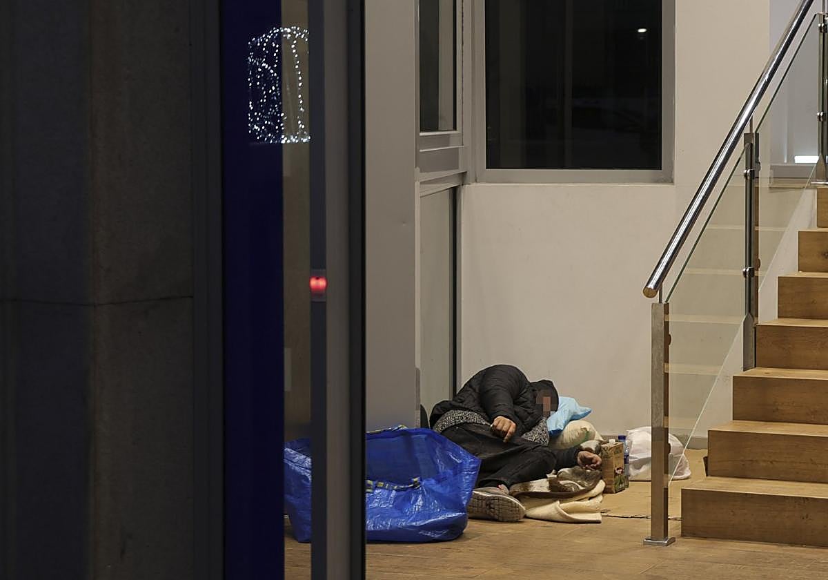 Un hombre duerme en la oficina bancaria en la que el pasado sábado falleció un 'sin techo'.