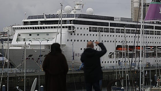 Dos personas observan el cruero 'Ambition' en A Coruña.