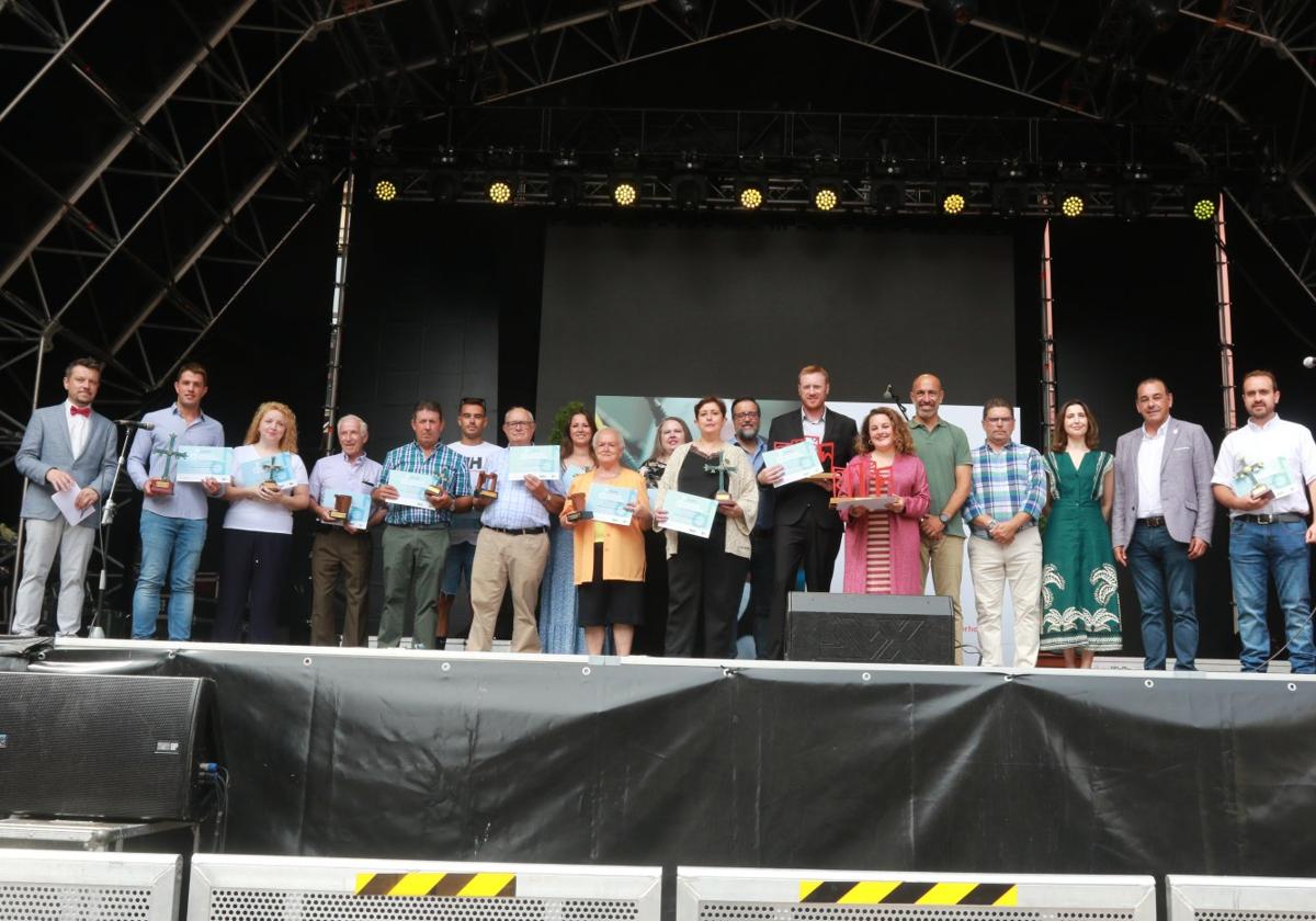 Las catorce mejores voces de la canción asturiana en categoría asbsoluta posan con sus premios junto a autoridades y patrocinadores en el escenario de la plaza Mayor.