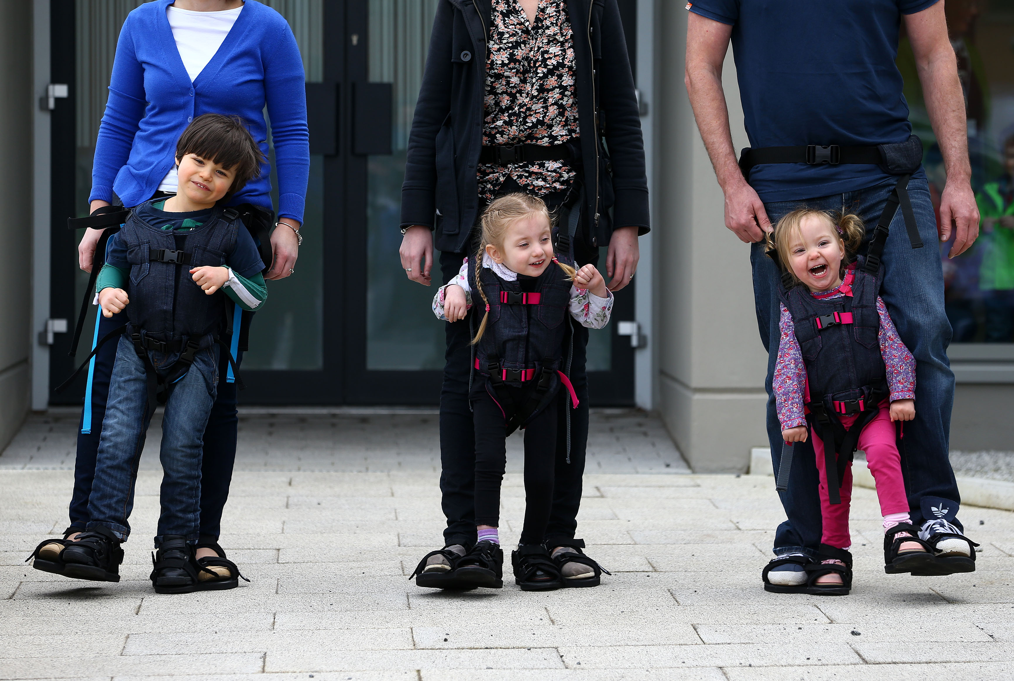 Tres niños con discapacidad caminan ayudados por el arnés Firefly Upsee