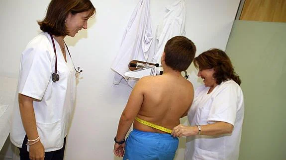 Una enfermera pesa y mide a un niño con sobrepeso. 