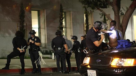Varios agentes cachean a detenidos en Los Ángeles. 
