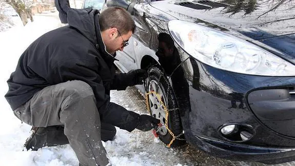 Un conductor coloca las cadenas a su vehículo. 