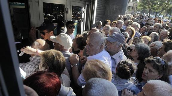 Cientos de pensionistas hacen cola a las puertas de un banco. 