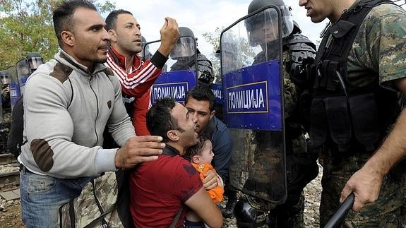 Un grupo de inmigrantes se dirige a los efectivos de las fuerzas de seguridad de Macedonia. 